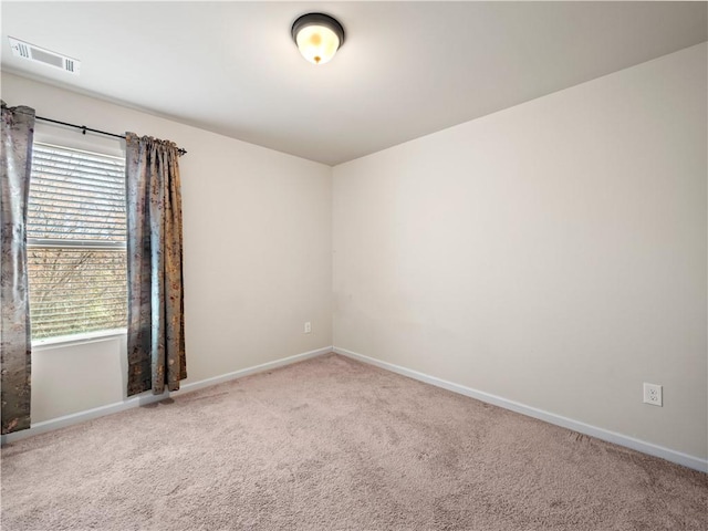 empty room with baseboards, visible vents, and carpet flooring