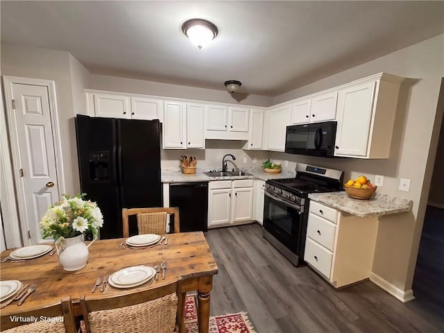 kitchen featuring dark wood-type flooring, black appliances, white cabinets, sink, and light stone countertops