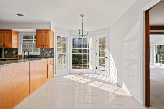 kitchen featuring an inviting chandelier, tasteful backsplash, stone countertops, decorative light fixtures, and light tile patterned floors