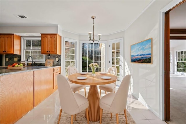 dining room with a chandelier, light tile patterned floors, ornamental molding, and sink