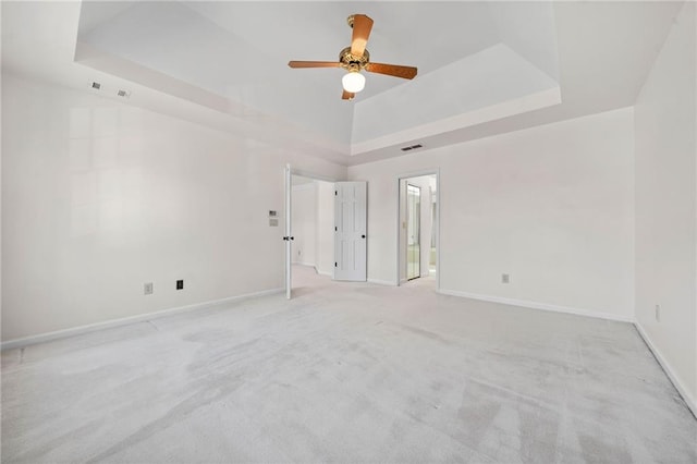 carpeted spare room featuring a raised ceiling and ceiling fan