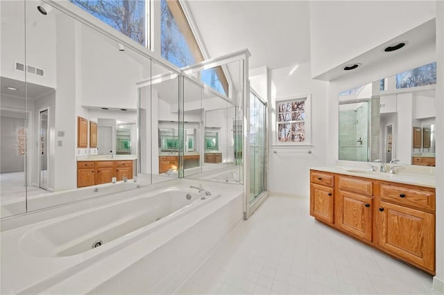 bathroom featuring plus walk in shower, a towering ceiling, vanity, and a healthy amount of sunlight