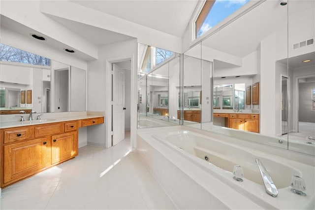 bathroom featuring tile patterned floors, a bathing tub, vanity, and lofted ceiling