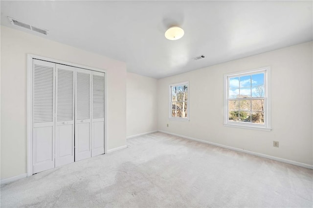 unfurnished bedroom featuring light colored carpet and a closet