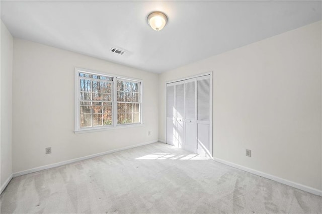 unfurnished bedroom with light carpet and a closet