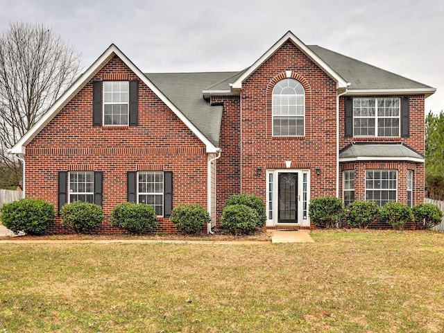 view of front of home with brick siding, a shingled roof, and a front lawn