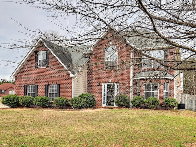 traditional home with a front yard, central air condition unit, fence, and brick siding