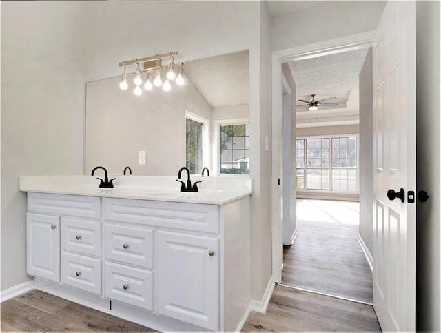 bathroom with double vanity, a ceiling fan, a sink, wood finished floors, and baseboards