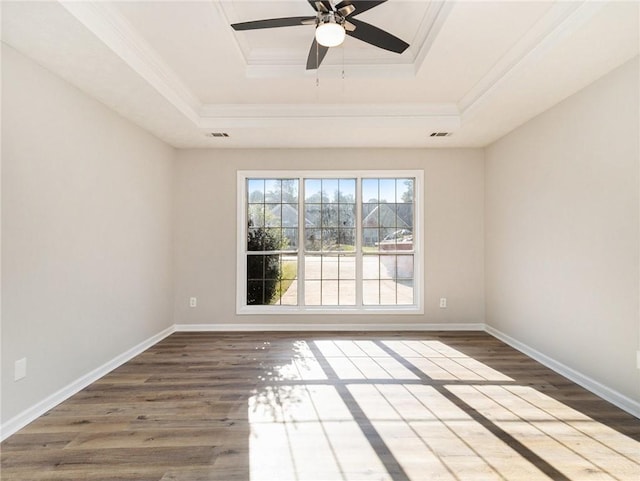 unfurnished room with baseboards, a raised ceiling, wood finished floors, and ornamental molding