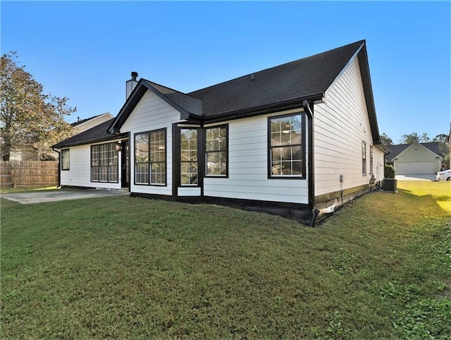 rear view of property featuring central AC, fence, a lawn, a chimney, and a patio area