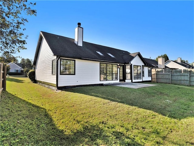 back of property with a chimney, fence, a patio, and a lawn