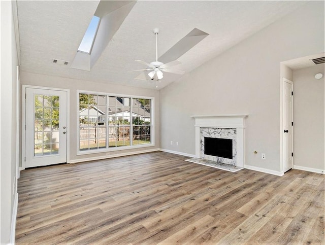 unfurnished living room with a premium fireplace, lofted ceiling with skylight, plenty of natural light, and wood finished floors