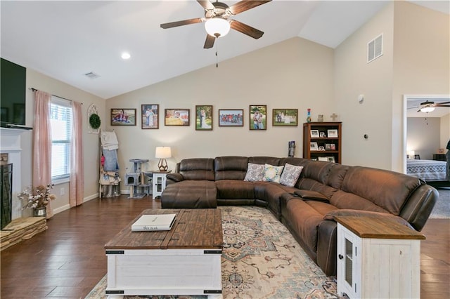 living room featuring a fireplace with raised hearth, wood finished floors, visible vents, and lofted ceiling