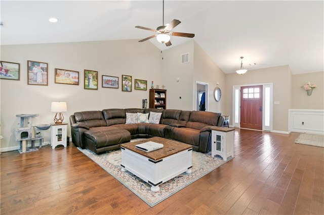 living room featuring high vaulted ceiling, hardwood / wood-style flooring, visible vents, and baseboards