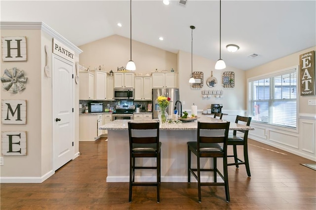 kitchen with stainless steel appliances, a kitchen island with sink, a kitchen breakfast bar, and dark wood-style floors