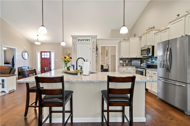 kitchen with appliances with stainless steel finishes, dark wood finished floors, a sink, and a breakfast bar area