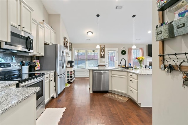 kitchen featuring a sink, hanging light fixtures, appliances with stainless steel finishes, backsplash, and dark wood finished floors