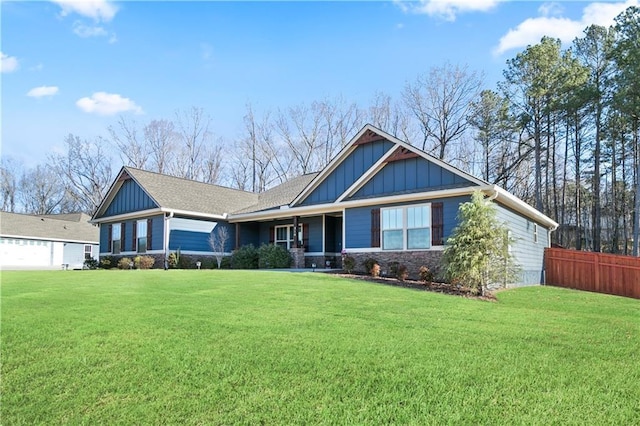 view of front of home featuring board and batten siding, stone siding, fence, and a front lawn