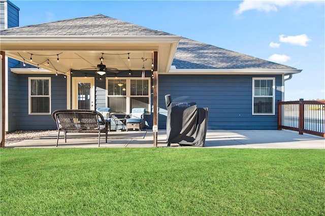 back of house featuring a patio, a yard, a shingled roof, and a ceiling fan