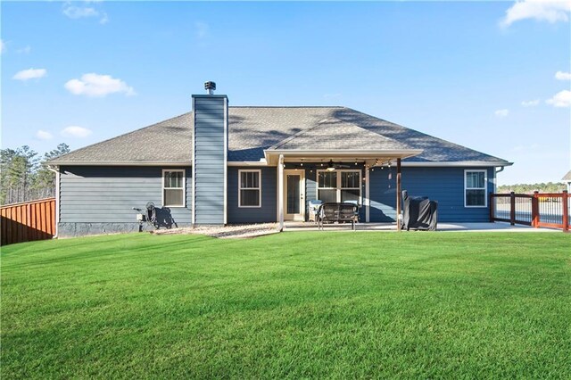 rear view of property featuring fence, a lawn, and a patio