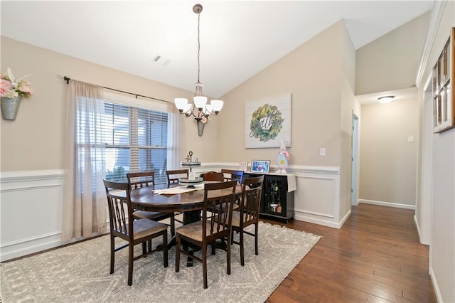 dining room with lofted ceiling, hardwood / wood-style flooring, a wainscoted wall, visible vents, and an inviting chandelier