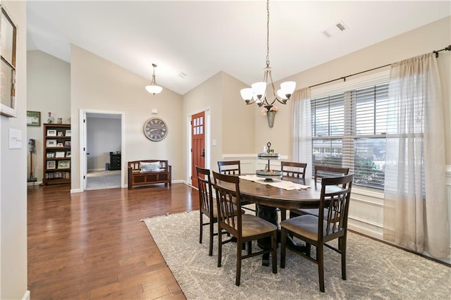 dining space featuring baseboards, visible vents, wood finished floors, an inviting chandelier, and high vaulted ceiling