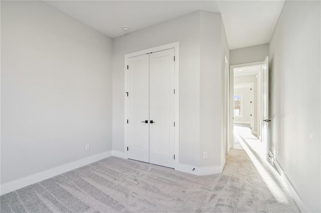 unfurnished bedroom with light carpet and a closet