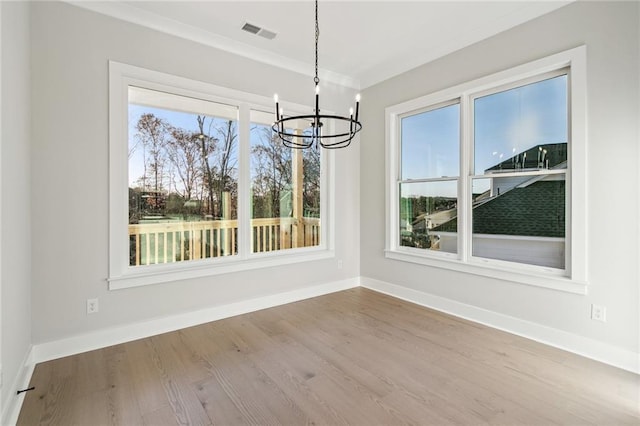 unfurnished dining area featuring hardwood / wood-style floors, ornamental molding, and a chandelier