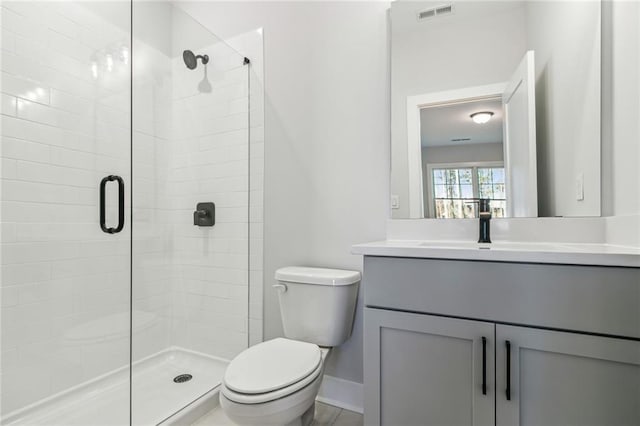 bathroom featuring vanity, toilet, and a shower with door