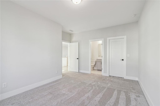 unfurnished bedroom featuring connected bathroom and light colored carpet