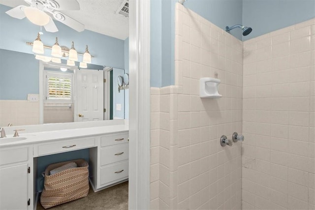 bathroom with vanity, tiled shower, and ceiling fan