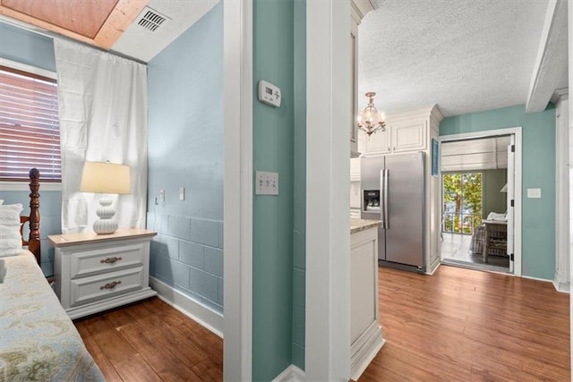 interior space featuring access to outside, a textured ceiling, dark wood-type flooring, and stainless steel fridge with ice dispenser