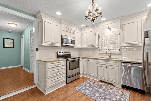 kitchen with sink, white cabinets, light hardwood / wood-style flooring, and stainless steel appliances