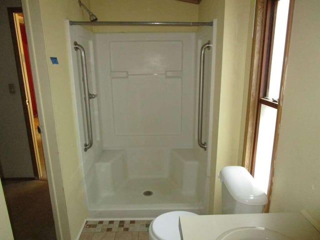 bathroom with walk in shower, tile patterned flooring, and toilet