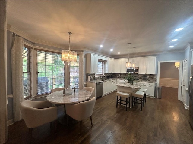 dining area with sink, a chandelier, crown molding, and dark hardwood / wood-style flooring