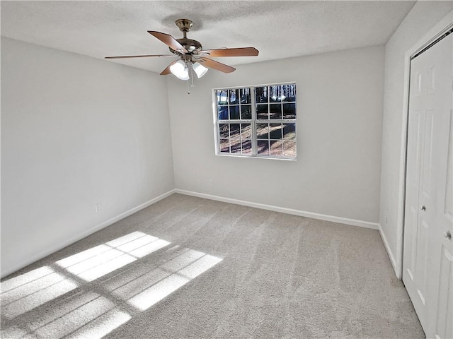 empty room with ceiling fan, light colored carpet, and a textured ceiling