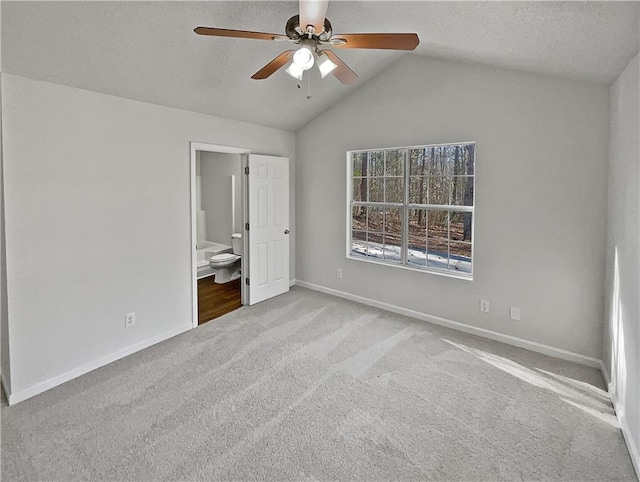 unfurnished bedroom featuring light carpet, ensuite bathroom, ceiling fan, and lofted ceiling