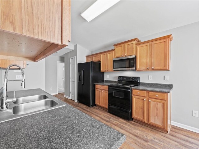 498 Walnut Woods Dr, Braselton, GA 30517 - kitchen with dark countertops, a sink, light wood-style flooring, lofted ceiling, and black appliances