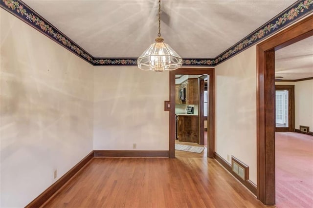 unfurnished dining area with an inviting chandelier and hardwood / wood-style flooring