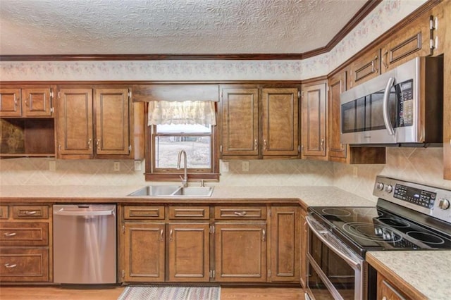 kitchen featuring sink, tasteful backsplash, a textured ceiling, stainless steel appliances, and light hardwood / wood-style floors