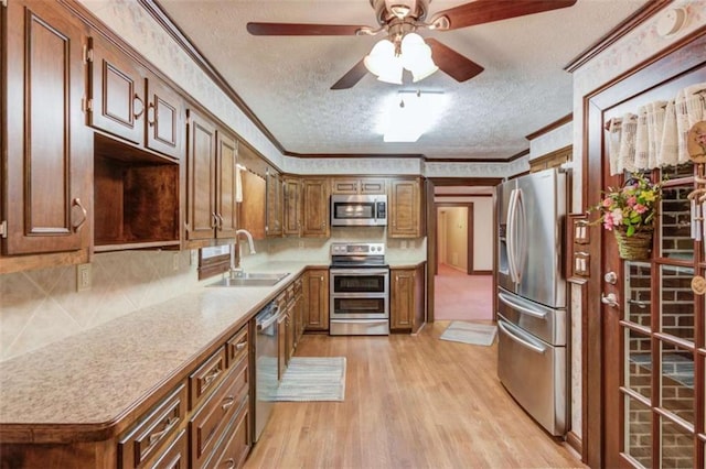 kitchen with ornamental molding, appliances with stainless steel finishes, sink, and a textured ceiling