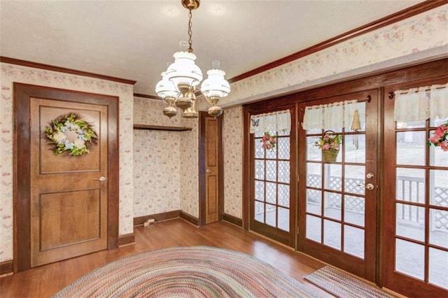 doorway featuring wood-type flooring, ornamental molding, french doors, and a chandelier