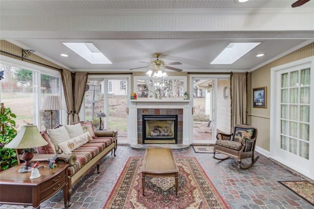 sunroom with a tiled fireplace, a skylight, and ceiling fan