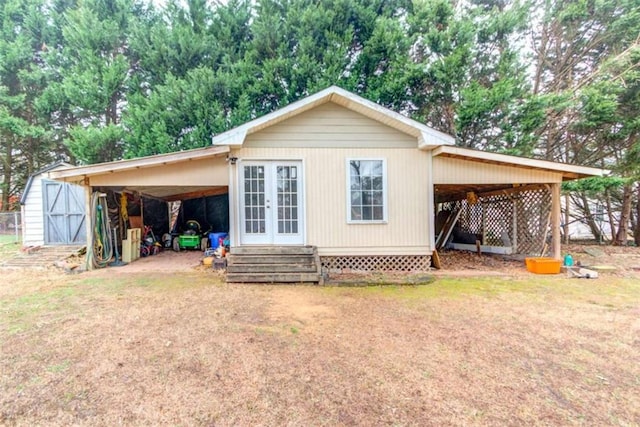 back of house featuring a carport, a lawn, and a storage unit