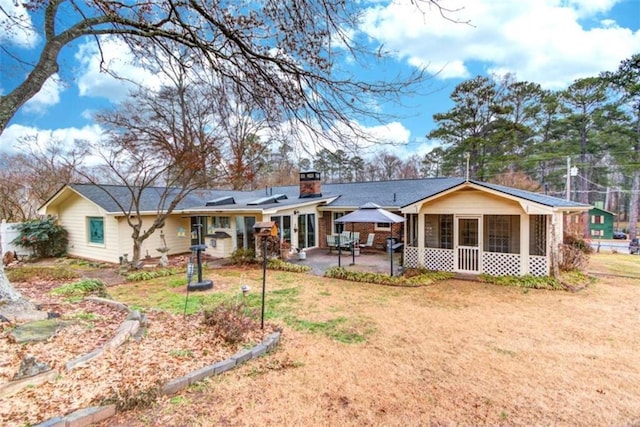 rear view of property with a yard, a sunroom, a patio area, and solar panels