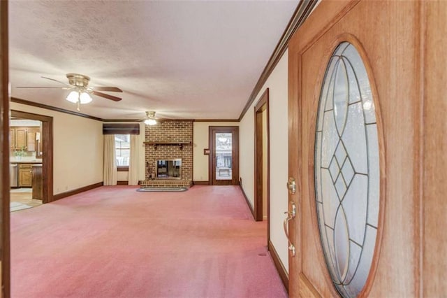 unfurnished living room with ceiling fan, carpet flooring, ornamental molding, a textured ceiling, and a brick fireplace