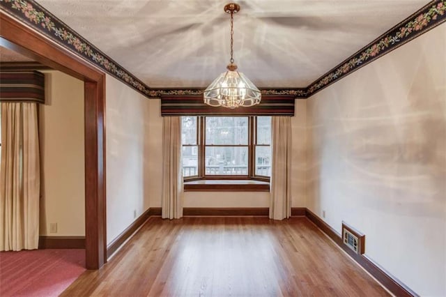 unfurnished dining area with an inviting chandelier and hardwood / wood-style floors