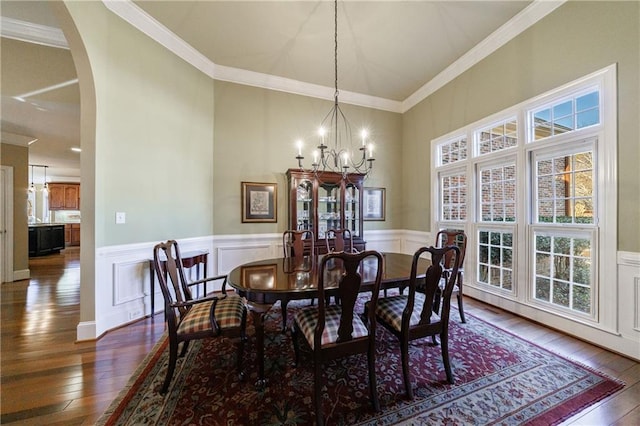 dining space featuring dark wood-type flooring, crown molding, and a chandelier