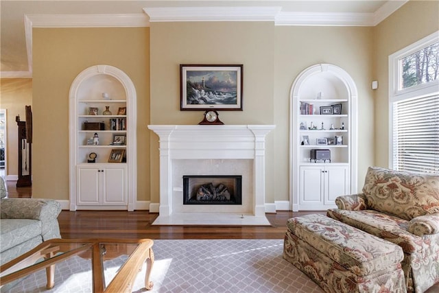 living room featuring dark wood-type flooring, ornamental molding, a premium fireplace, and built in features