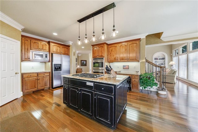 kitchen featuring pendant lighting, appliances with stainless steel finishes, light stone countertops, a kitchen island, and dark hardwood / wood-style flooring